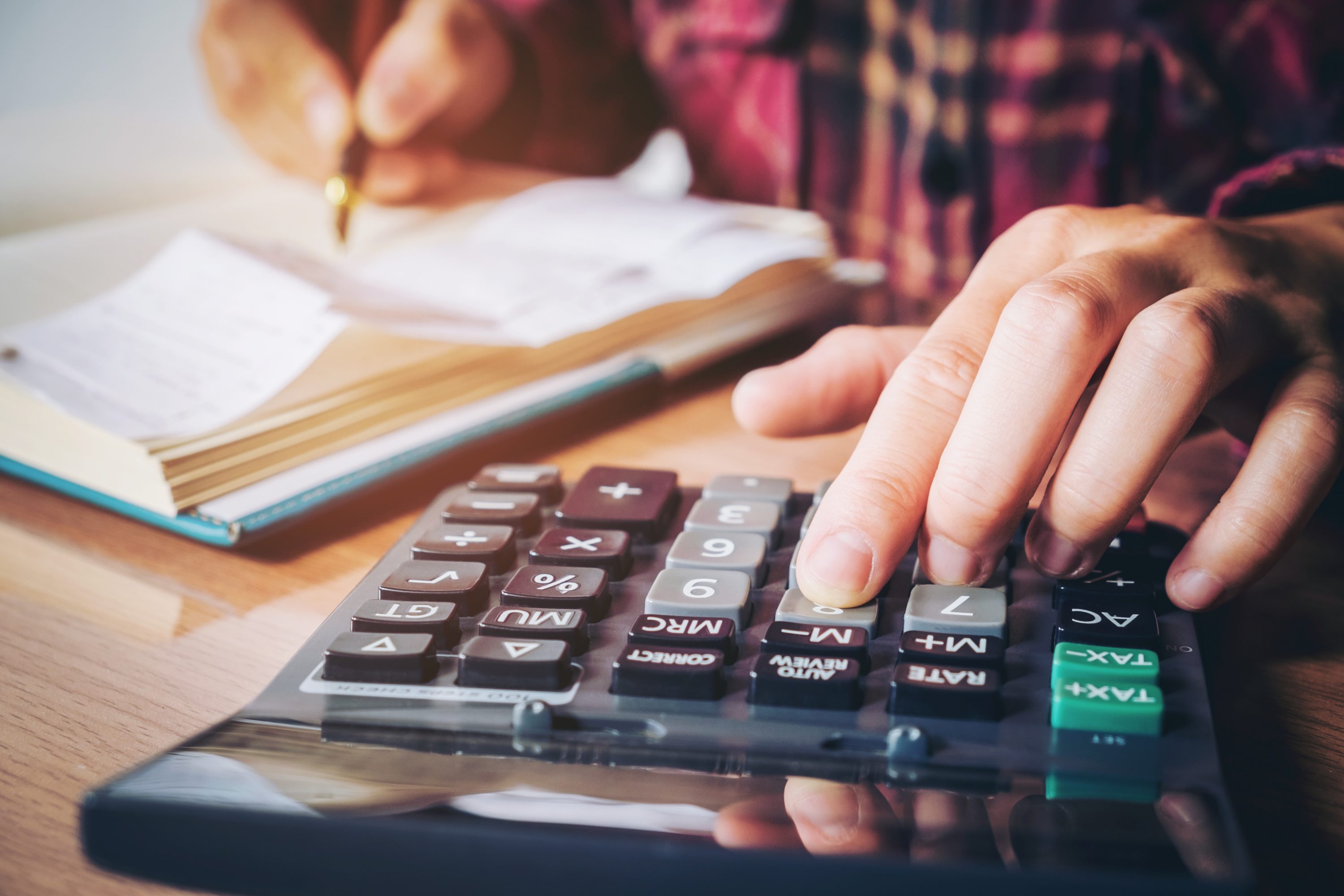 Businessman's hands with calculator and cost at the office and Financial data analyzing counting on wood desk