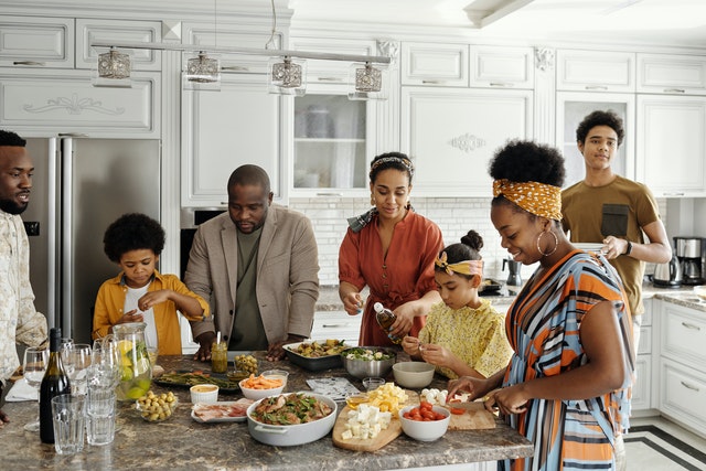 A large family gathered in the kitchen to cook together.