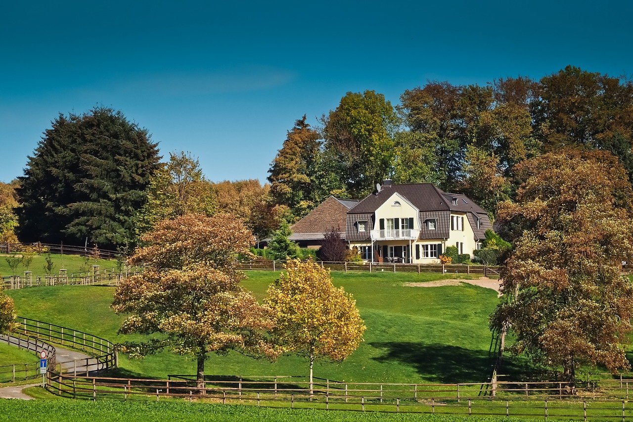 A property in a rural area - a house, fence, and many trees