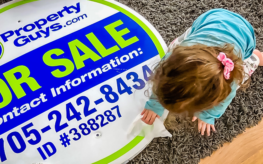 Child cleaning real estate for sale sign