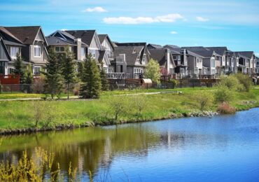 Canadian suburb, row of houses near water, clear sky, green grass